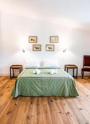 a bedroom with a bed with green bedspread and wooden floors at La tonnelerie, belle villa pour 9 personnes au coeur d'un vignoble avec piscine in Sartène