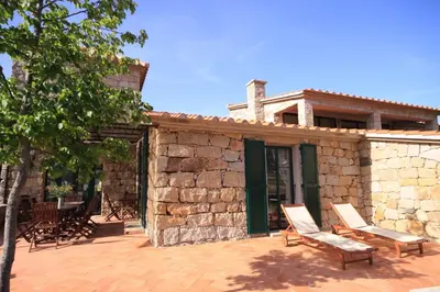 a stone building with two chairs and a house at Les anciennes écuries, belle villa pour 12 personnes au coeur d'un vignoble avec piscine in Sartène