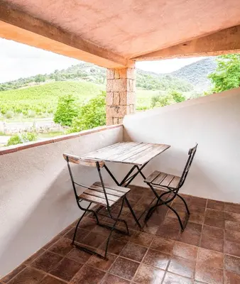 a table and two chairs on a balcony with a view at Les anciennes écuries, belle villa pour 12 personnes au coeur d'un vignoble avec piscine in Sartène