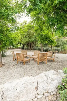 a group of wooden benches sitting in a park at Le chai, belle villa pour 13 personnes au coeur d'un vignoble avec piscine in Sartène