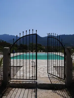 an open gate to a swimming pool with the water at Le chai, belle villa pour 13 personnes au coeur d'un vignoble avec piscine in Sartène