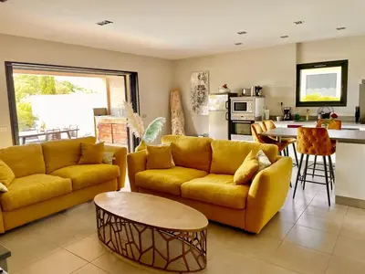 a living room with yellow couches and a kitchen at Villa Mare piscine et spa in Zonza