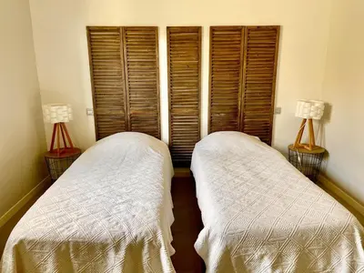 two beds in a room with wooden shutters at Villa Mare piscine et spa in Zonza