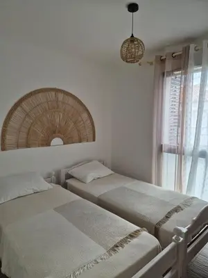 two beds in a bedroom with a mirror and a window at Appartement 4 pers en résidence in Propriano