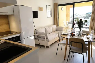 a kitchen and living room with a couch and a table at Le Loria - T3 vue mer avec piscine in Pianottoli-Caldarello
