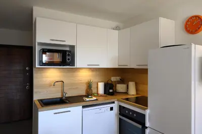 a kitchen with white cabinets and a sink and a microwave at Le Loria - T3 vue mer avec piscine in Pianottoli-Caldarello