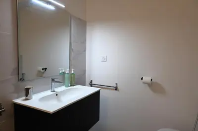 a white bathroom with a sink and a mirror at Le Loria - T3 vue mer avec piscine in Pianottoli-Caldarello