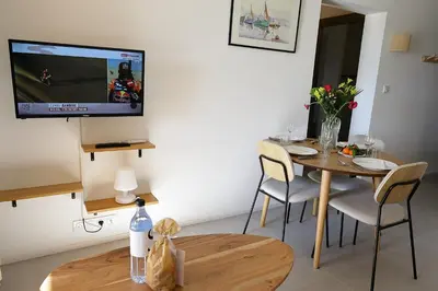 a living room with a table and a tv on the wall at Le Loria - T3 vue mer avec piscine in Pianottoli-Caldarello