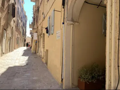 an alley with a building and a person walking down the street at Appartement citadelle Bonifacio Appolonie in Bonifacio