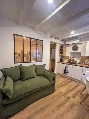 a living room with a green couch and a kitchen at Appartement citadelle Bonifacio Appolonie in Bonifacio