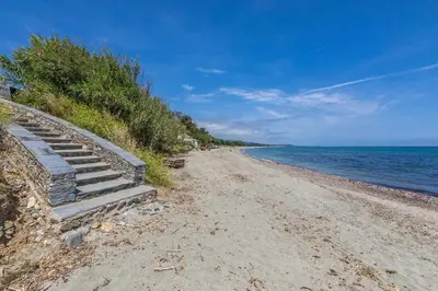 a sandy beach with steps leading to the ocean at Résidence hôtelière D'Amare in Cervione