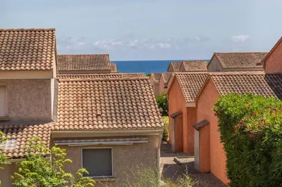 a row of houses with the ocean in the background at Résidence hôtelière D'Amare in Cervione