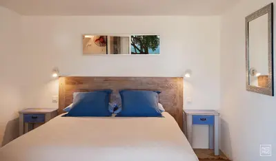 a bedroom with a large bed with blue pillows at Chambres d'Hôtes Littariccia in Porto-Vecchio