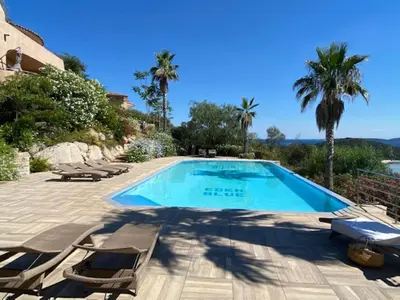 a swimming pool with chaise lounge chairs and a villa at Villa eden blue F4 3 in Zonza