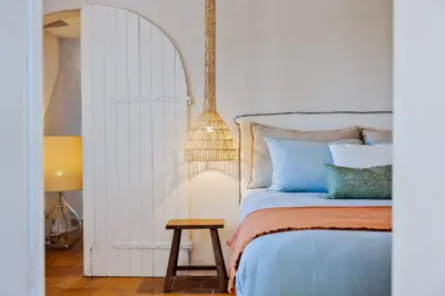 a bedroom with a bed and a table and a lamp at La Maison sur la plage - Les pieds dans l'eau in Bonifacio
