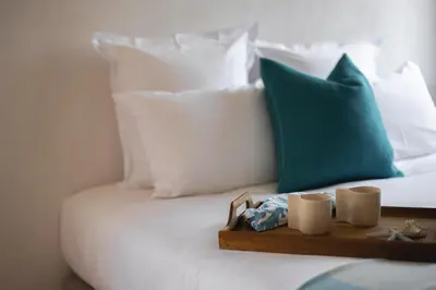a tray on a bed with a green pillow and mugs at La Maison sur la plage - Les pieds dans l'eau in Bonifacio