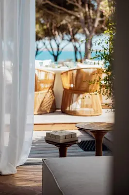 a table and chairs on a patio with a view of the ocean at La Maison sur la plage - Les pieds dans l'eau in Bonifacio