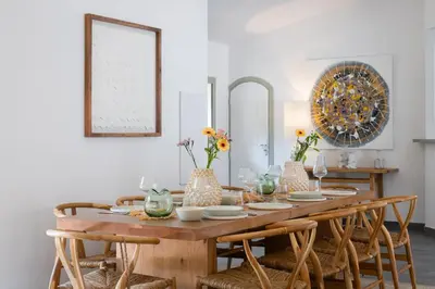 a dining room with a wooden table and chairs at La Maison sur la plage - Les pieds dans l'eau in Bonifacio