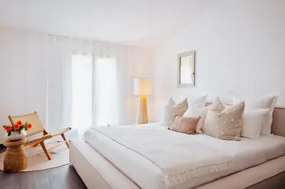 a white bedroom with a large white bed with pillows at La Maison sur la plage - Les pieds dans l'eau in Bonifacio