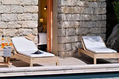 two chairs sitting on a deck next to a pool at Les bergeries alivaccia in Figari