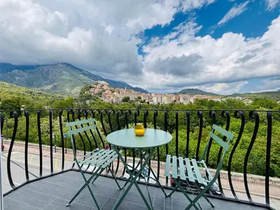 a table and two chairs on a balcony with mountains at Straboni corte in Corte