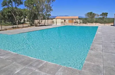 a swimming pool with blue water in a yard at BONIFACIO Villa U ARANCIU in Bonifacio