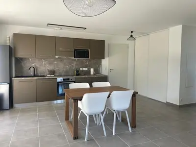 a kitchen with a wooden table and white chairs at Appartement Solaro, plage à 100m in Solaro