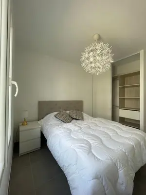 a bedroom with a large white bed and a chandelier at Appartement Solaro, plage à 100m in Solaro