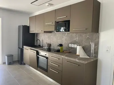 a kitchen with brown cabinets and a black refrigerator at Appartement Solaro, plage à 100m in Solaro
