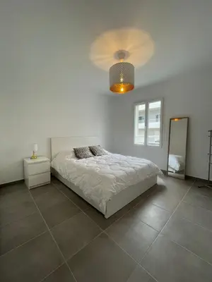 a white bedroom with a bed and a mirror at Appartement Solaro, plage à 100m in Solaro