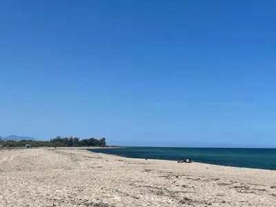 two people laying on a beach next to the water at Appartement Solaro, plage à 100m in Solaro