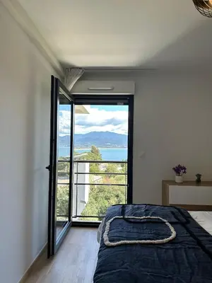 a bedroom with a bed and a large window at Torriciola location Genovese in Ajaccio