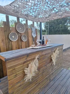 a bar on a wooden deck with a table at Villa Jessy Porto-Vecchio in Porto-Vecchio