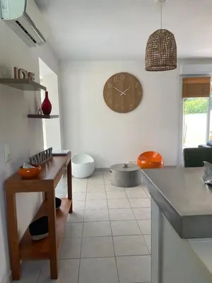 a kitchen with a clock on the wall and a table at Villa Jessy Porto-Vecchio in Porto-Vecchio