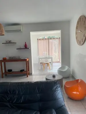 a living room with a couch and a clock on the wall at Villa Jessy Porto-Vecchio in Porto-Vecchio