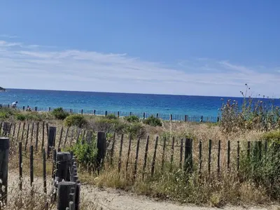 a fence on a beach with the ocean in the background at Vos vacances à 3 minutes de la mer in Belgodère