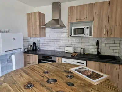 a kitchen with a wooden table in the middle of it at Vos vacances à 3 minutes de la mer in Belgodère
