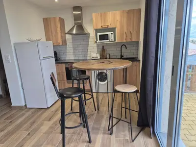a kitchen with a table and chairs and a refrigerator at Vos vacances à 3 minutes de la mer in Belgodère
