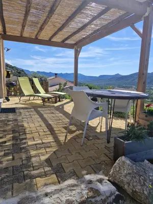 a patio with a table and chairs under a pergola at Vos vacances à 3 minutes de la mer in Belgodère