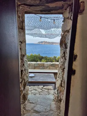 a view of the ocean from a stone doorway at Vos vacances à 3 minutes de la mer in Belgodère