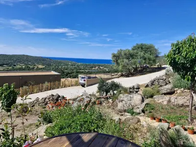 a bus is driving down a road with rocks and a road at Vos vacances à 3 minutes de la mer in Belgodère