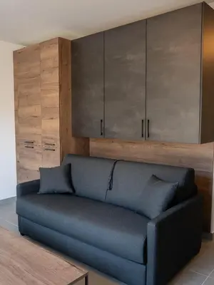 a blue couch in a living room with wooden cabinets at Studio moderne et lumineux, proche centre ville in Propriano