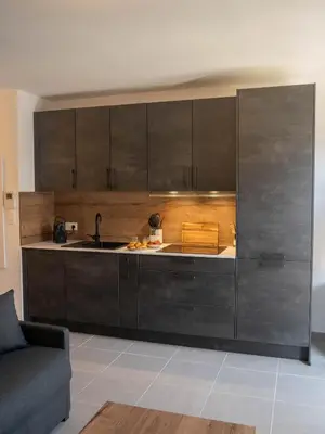 a kitchen with black cabinets and a couch at Studio moderne et lumineux, proche centre ville in Propriano