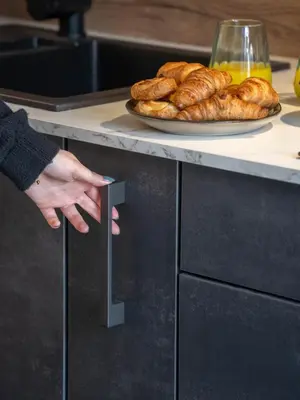 a person pointing at a counter with a plate of bread at Studio moderne et lumineux, proche centre ville in Propriano