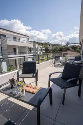 a patio with two chairs and a table on a balcony at Studio moderne et lumineux, proche centre ville in Propriano