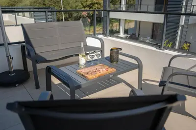 a table with a pizza and two glasses on a balcony at Studio moderne et lumineux, proche centre ville in Propriano