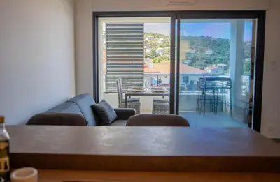 a living room with a couch and a view of a balcony at Charmant T2 proche centre ville et terrasse in Propriano