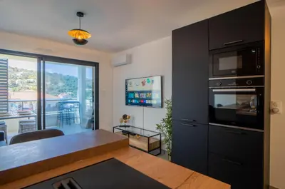 a living room with a kitchen with a table and a microwave at Charmant T2 proche centre ville et terrasse in Propriano