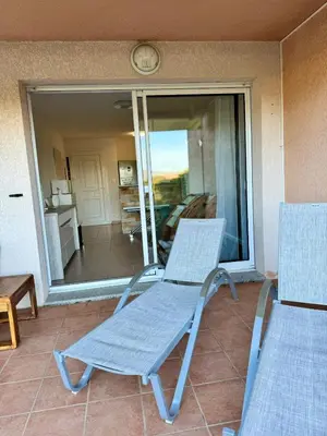 a pair of chairs sitting on a porch at Appart résidence avec piscine in Propriano