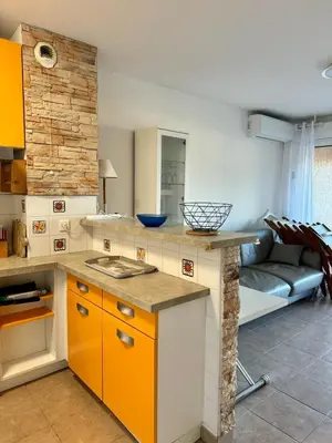 a kitchen with orange and white cabinets and a couch at Appart résidence avec piscine in Propriano